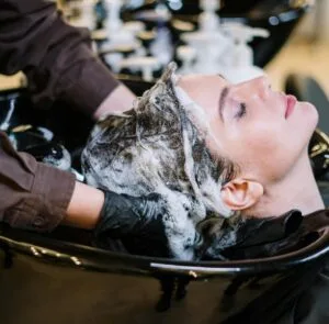Professional hair stylist washing woman's hair in a modern salon setting.