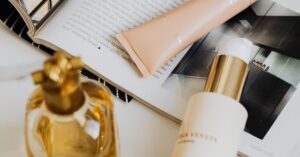 Aesthetic flat lay of perfume and cosmetics on a marble surface with magazine.