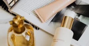 Aesthetic flat lay of perfume and cosmetics on a marble surface with magazine.